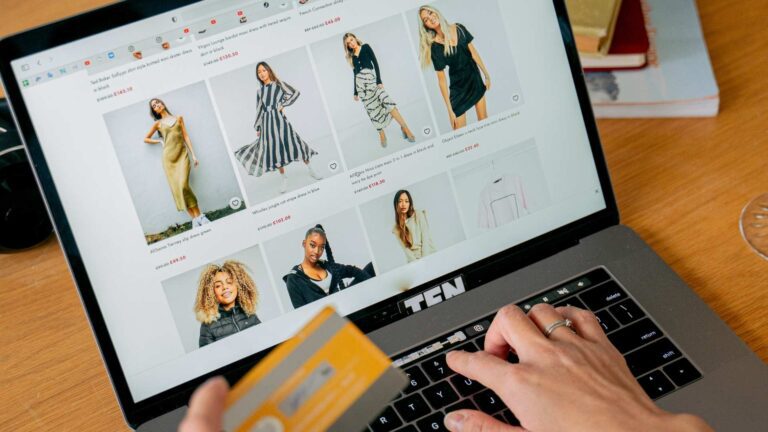Person using laptop for online shopping, browsing fashion items, and holding a credit card, illustrating e-commerce trends in retail.