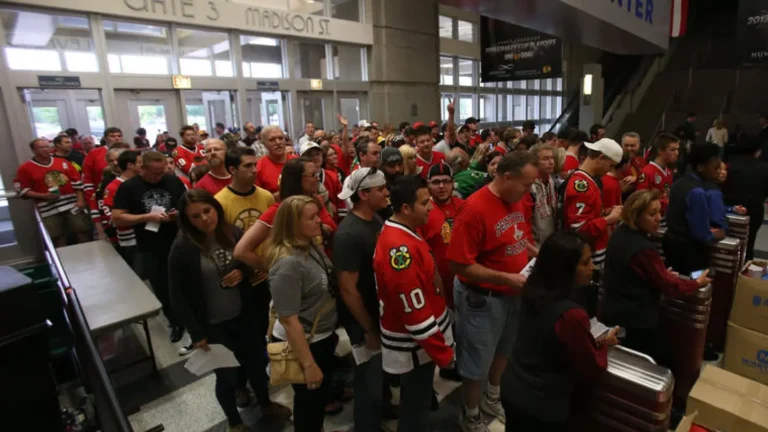 Crowd of sports fans in red jerseys waiting in line at a venue entrance, highlighting the retail environment and high-traffic context for RFID technology applications in merchandise management.